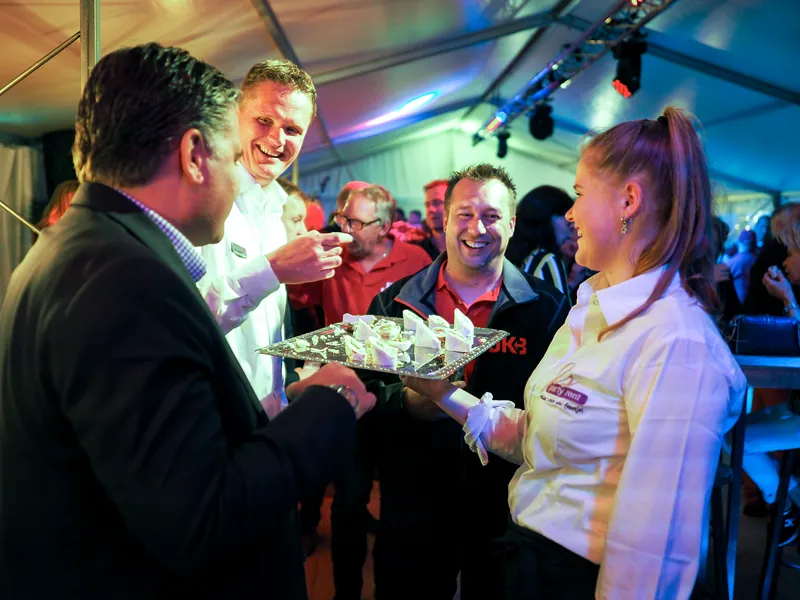 Gasten krijgen hapjes aangeboden in een feesttent tijdens een bedrijfsevenement