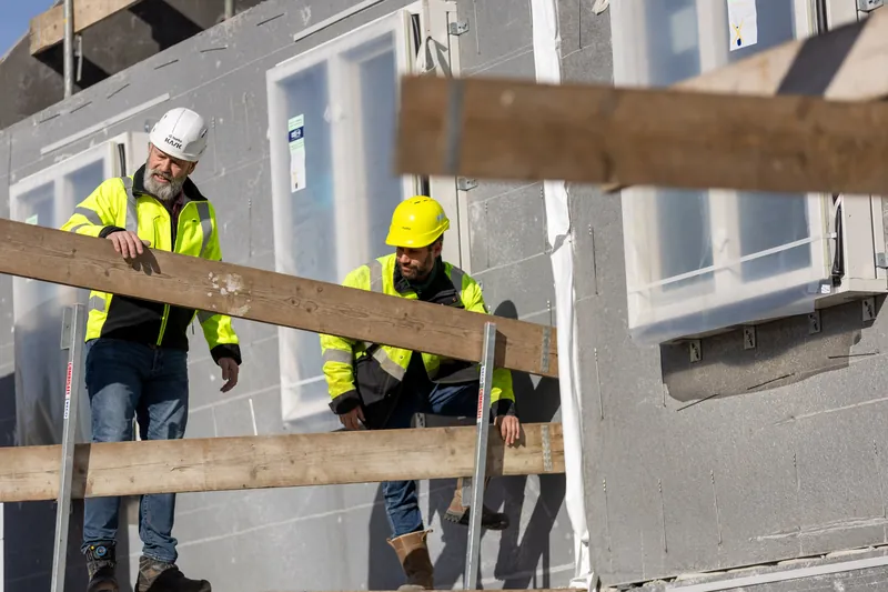 Bedrijfsreportage: twee bouwvakkers aan het werk bij een casco van een woning