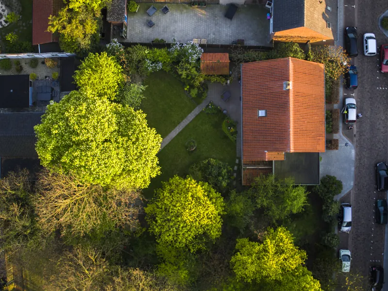 Dronefoto recht van boven op een straat met huizen en groene tuinen