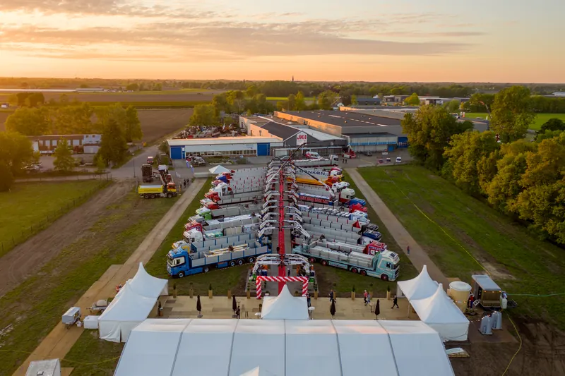 Dronefoto van een evenementterrein met rode loper en tenten bij avondlicht