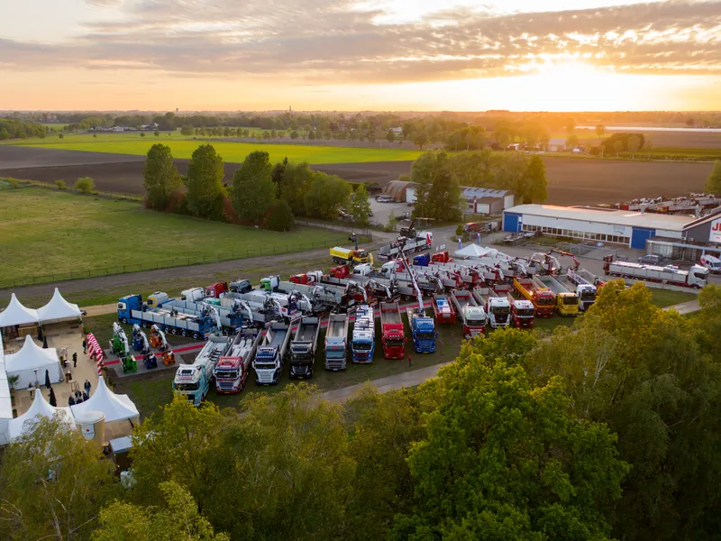 Dronefoto bij zonsondergang van een evenementterrein met vrachtwagens en tenten