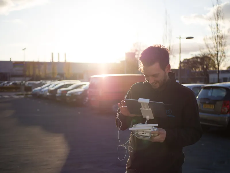 Niels van Tongerloo lacht terwijl hij met zijn drone controller aan het werk is bij zonsondergang