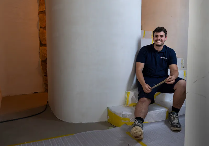 Bedrijfsreportage: lachende vakman zit ontspannen in een woning in aanbouw