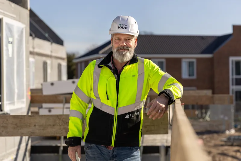 Portret van een man met bouwhelm en geel hesje op een bouwplaats