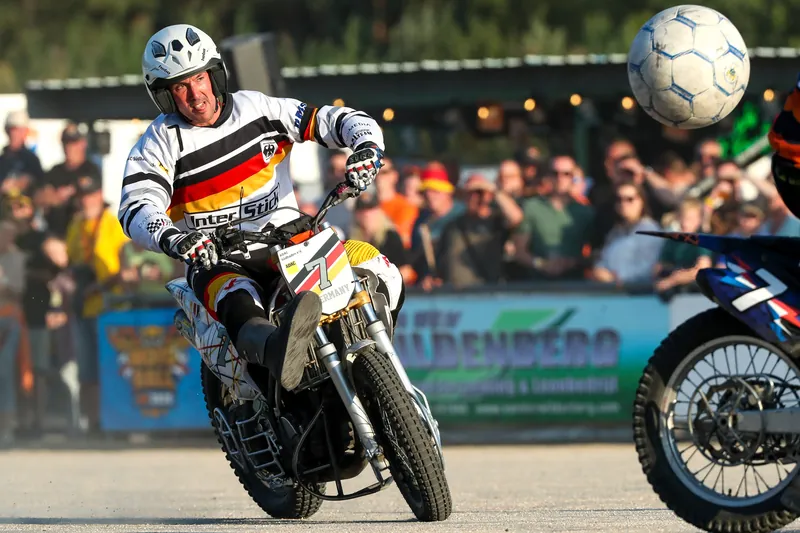 Motoballspeler in zwart rood geel shirt trapt de bal weg